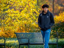 Student walking on path under vibrant fall foliage