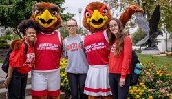 Three students in Montclair apparel posing with Rocky and Roxy in a campus green space