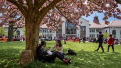 Two students sitting under a tree on Montclair State University's campus. The Open House events provide an opportunity for prospective students to experience campus life firsthand.