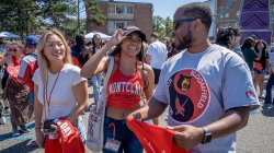 Two Montclair State University students and one Bloomfield College student stand together, chatting at an outdoor carnival.